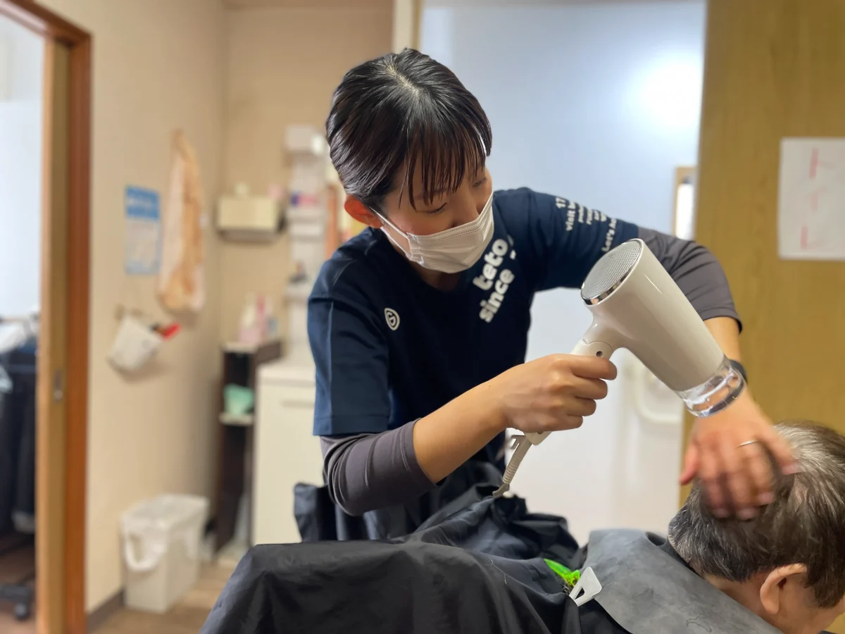 アシスタント業務でブローする訪問美容師の女性